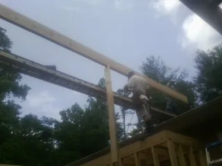 Carpenter setting a ridge beam over a new addition frame — Ice Dam Removal by Roofing Brothers in Edgewood
