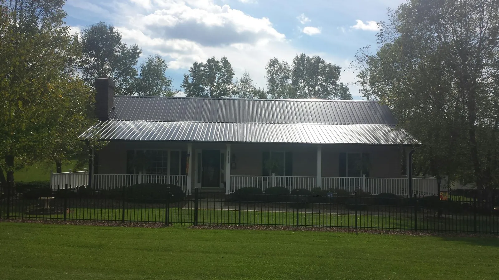 Gray metal roof on a brick ranch with a full width front porch — Gutter Guard Installation work by our crew in Edgewood